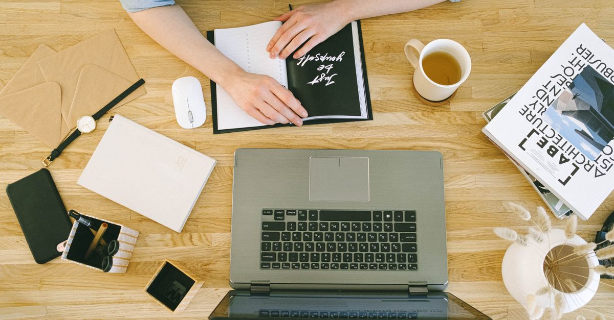 Top-down view of a home office desk with a laptop, coffee, and notes, perfect for freelance work or studying.